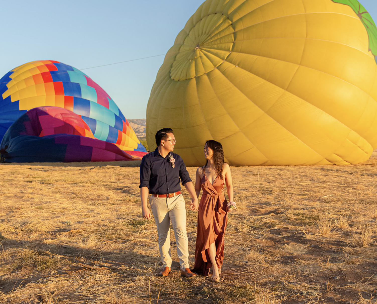 queer couple in front of colorful hot air balloons